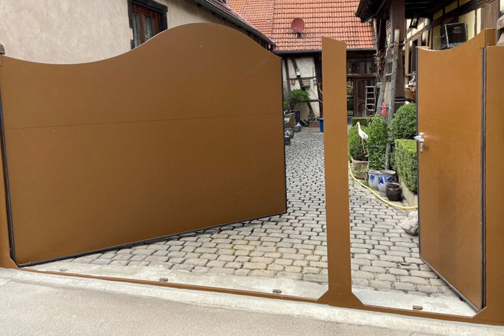 AquaLOCK® Hochwasserschutz‑Portal, maßgefertigt und geöffnet vor einer Grundstückseinfahrt