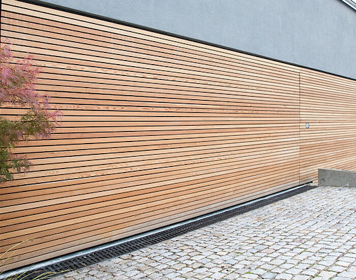 Großes geschlossenes Hochwasserschutz‑Schwingtor mit Holzoptik