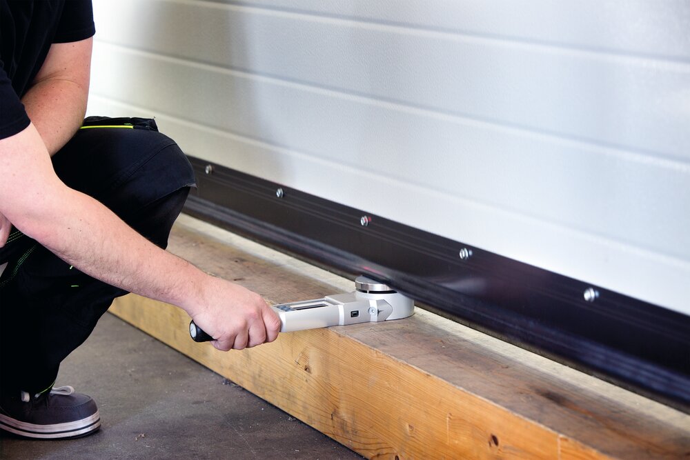 Handwerker testet die Abdichtung eines Garagentors
